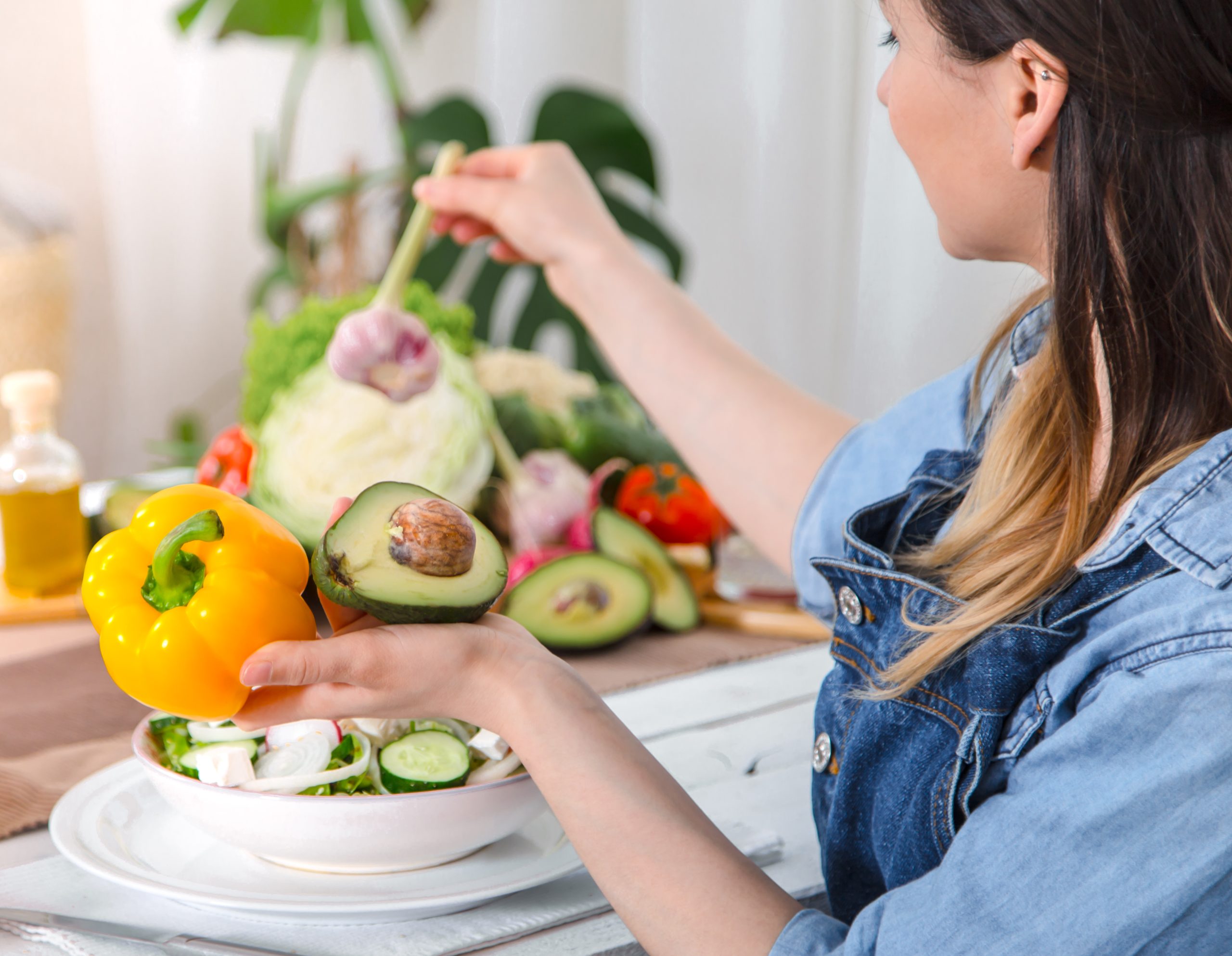 Young and happy woman eating salad at the table