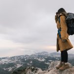 young-woman-with-her-backpack-standing-top-mountain-looking-idyllic-view