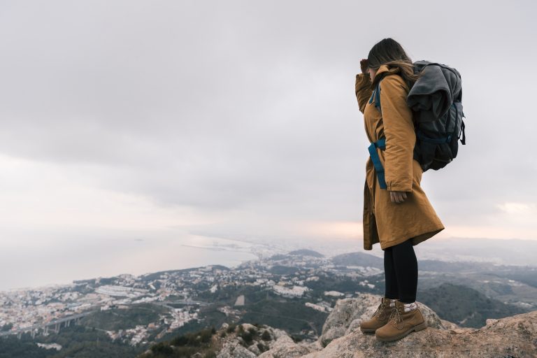 young-woman-with-her-backpack-standing-top-mountain-looking-idyllic-view